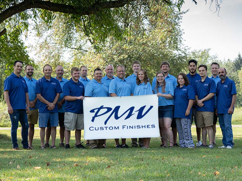 the staff of PMV Custom Finishes holding a banner