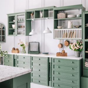 Cottage style kitchen with green cabinets and white countertops.